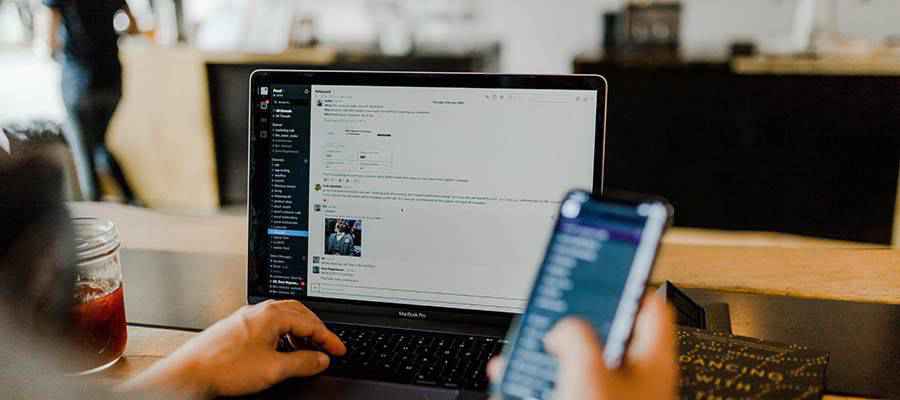 Person using a phone and laptop computer.